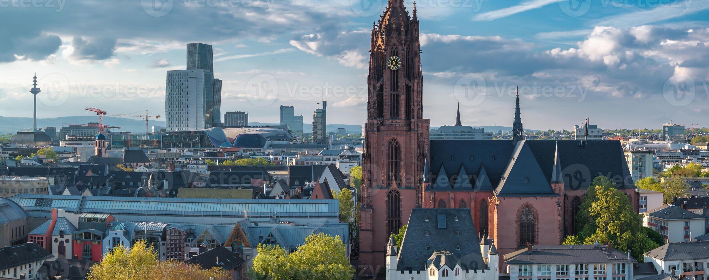 Aerial view of Frankfurt, Germany, featuring the Gothic style Frankfurt Cathedral and modern skyscrapers under a partly cloudy sky. photo