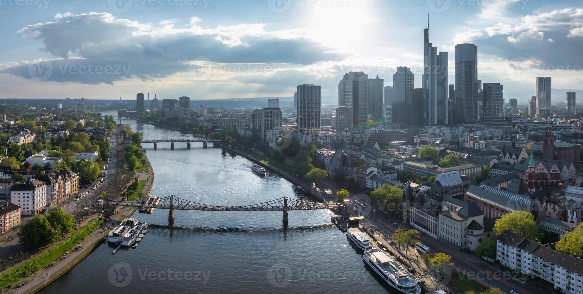 Aerial view of Frankfurt, Germany, featuring the Main River, Commerzbank Tower, Frankfurt Cathedral, Eiserner Steg, and greenery along the riverbanks. photo