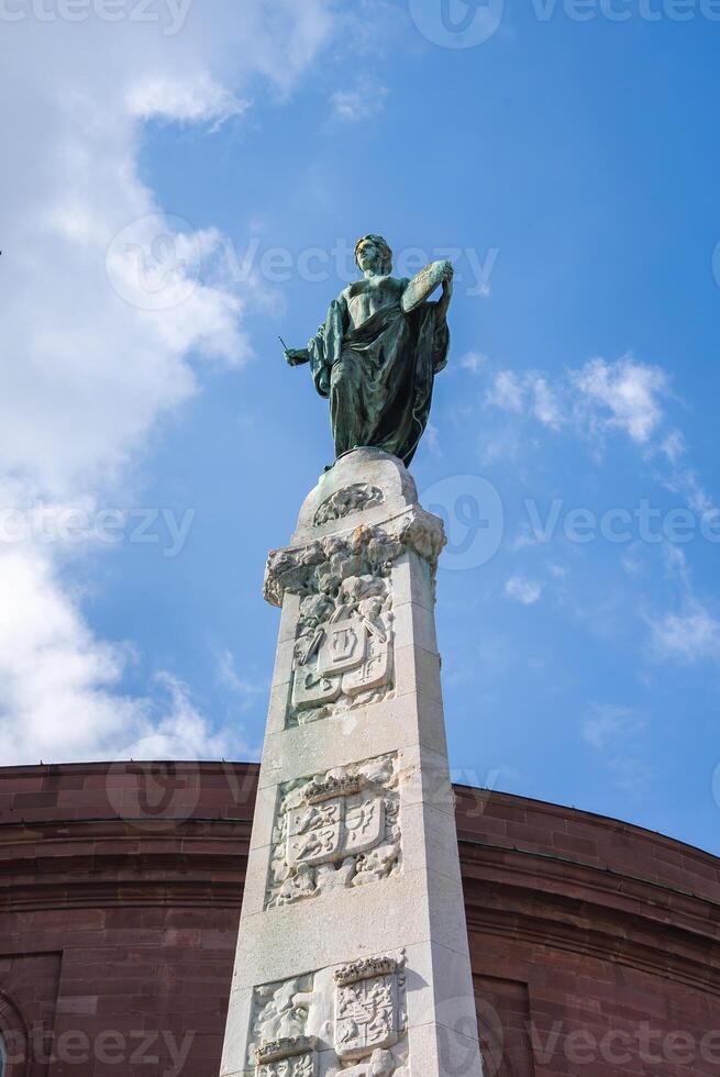 Stone Column with Bronze Statue and Red Sandstone Building in Frankfurt photo