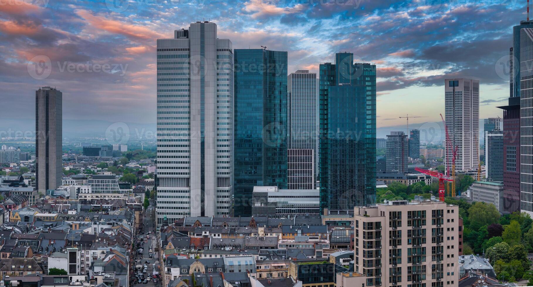 Aerial view of Frankfurt, Germany, showcasing the skyline with Eurotower, modern skyscrapers, traditional architecture, and a vibrant sunset sky. photo