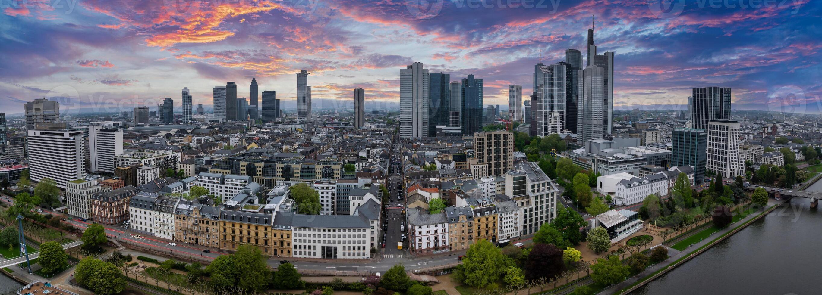Aerial view of Frankfurt, Germany, featuring the skyline with Commerzbank Tower, Main Tower, tree lined streets, and the Main River at sunset. photo
