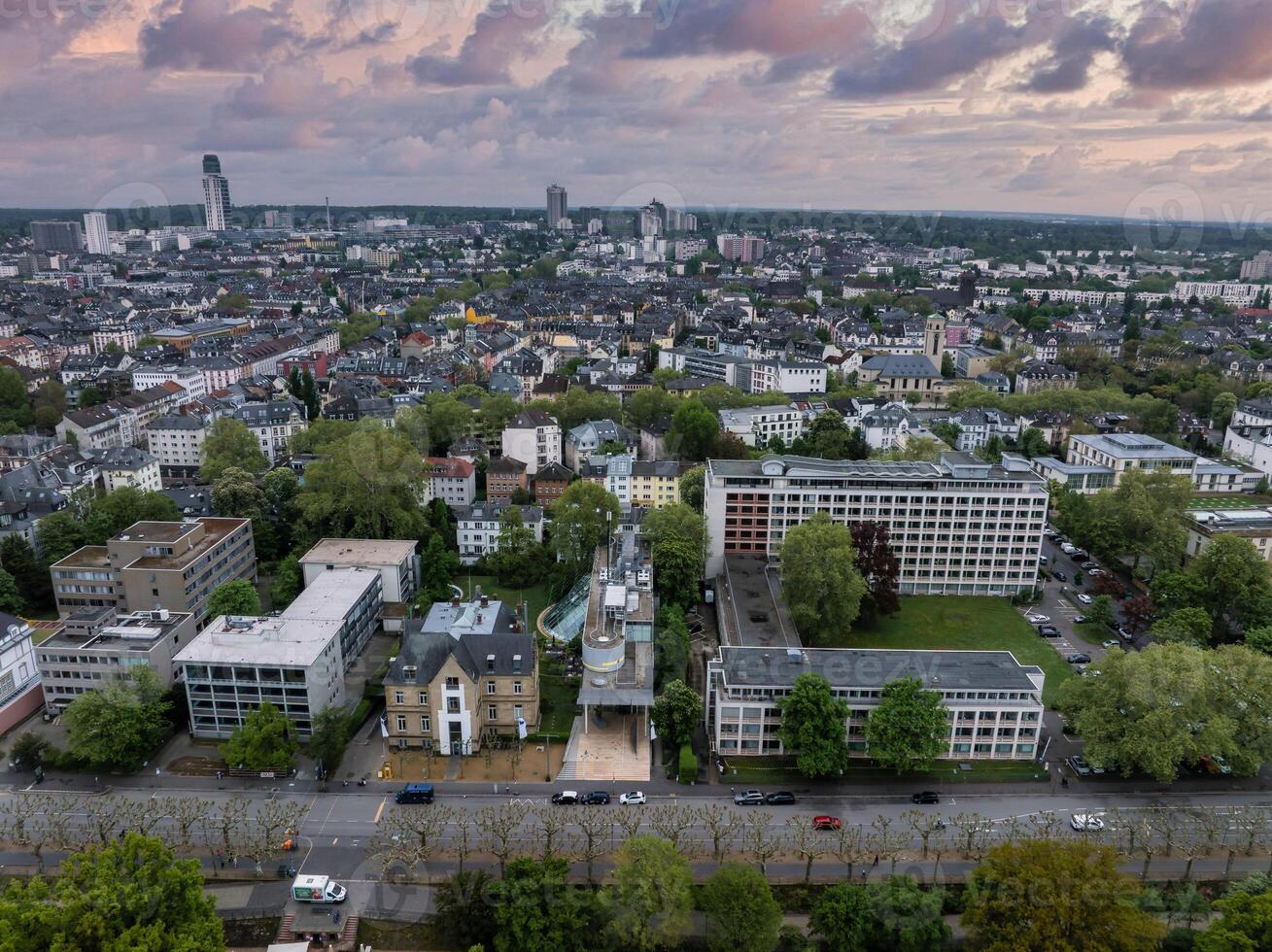 Aerial image of Frankfurt, Germany, showing mid sized buildings, greenery, and a dense urban area with a distinctive high rise under a cloudy sky. photo