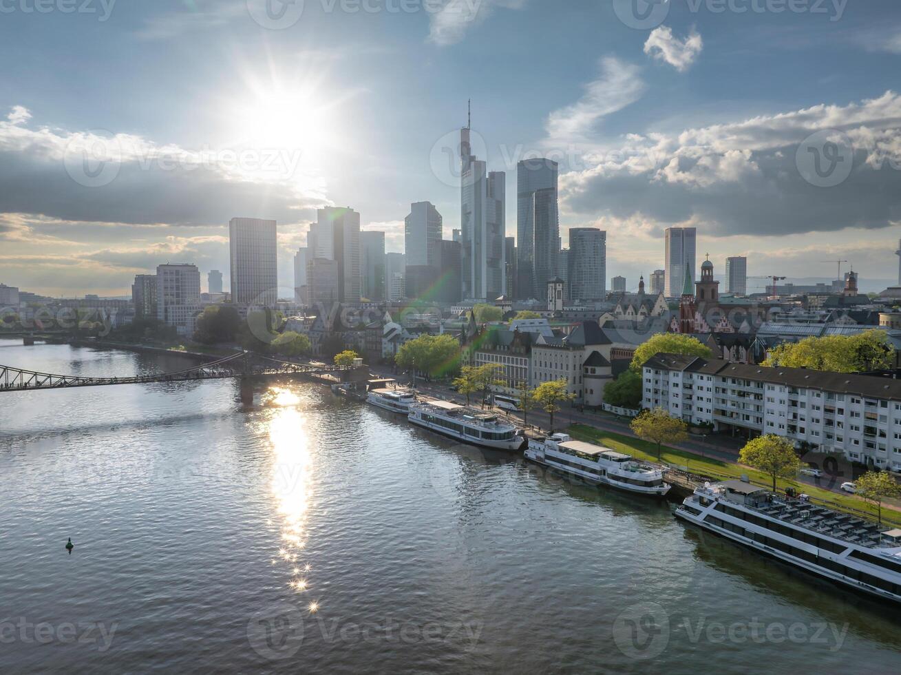 Aerial view of Frankfurt, Germany, featuring modern skyscrapers like Commerzbank Tower, the Main River with docked boats, and historic architecture. photo