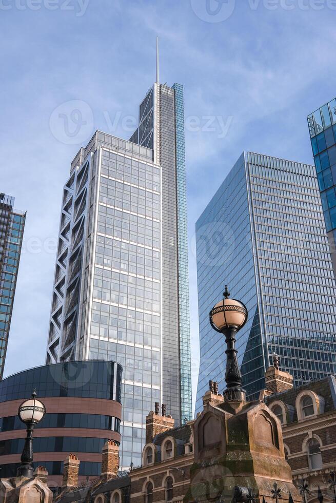 View of London's urban landscape featuring 22 Bishopsgate skyscraper, historic buildings, ornate street lamps, and a clear blue sky. photo