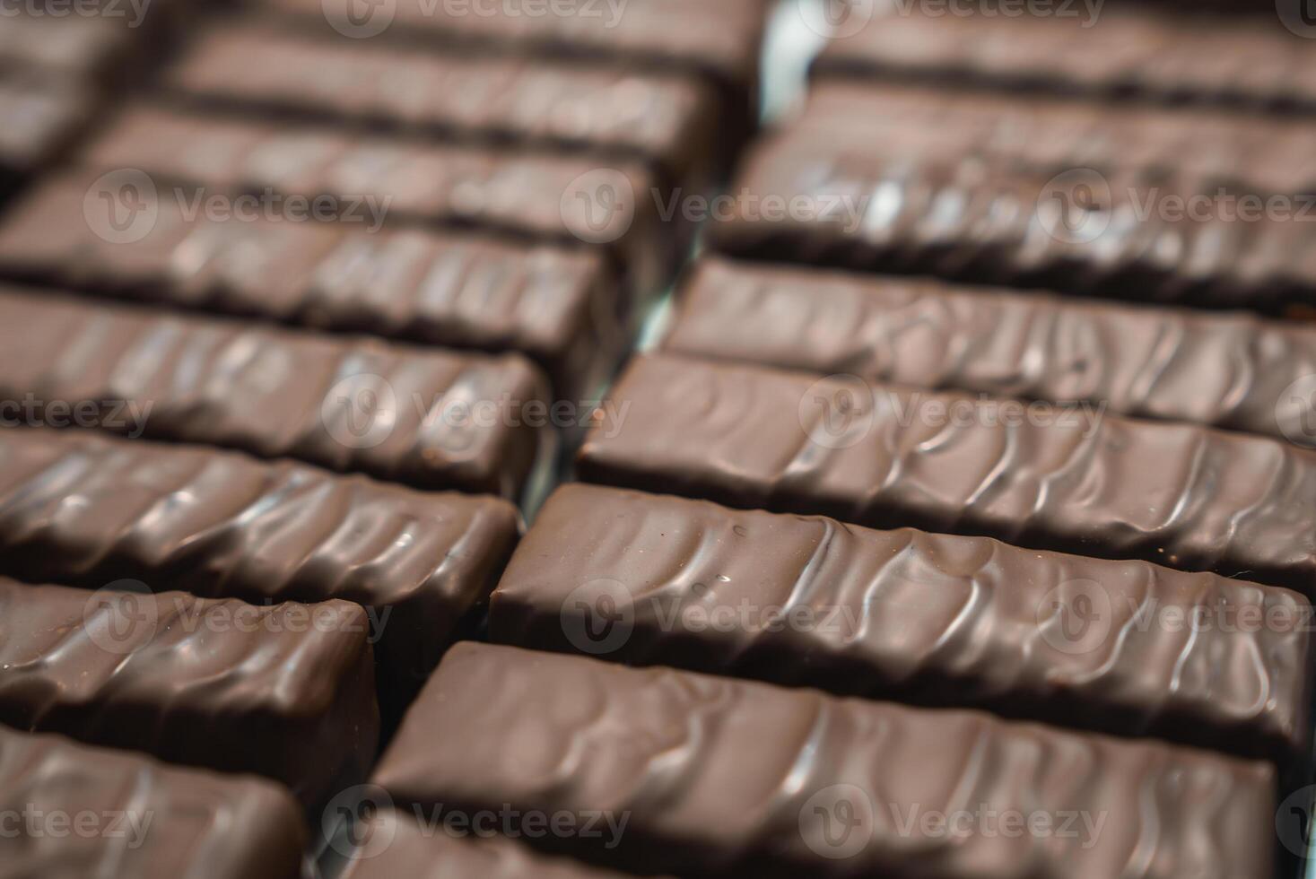 Neatly arranged chocolate bars with a glossy finish and wavy texture, aligned in rows to create a uniform and visually appealing pattern. photo