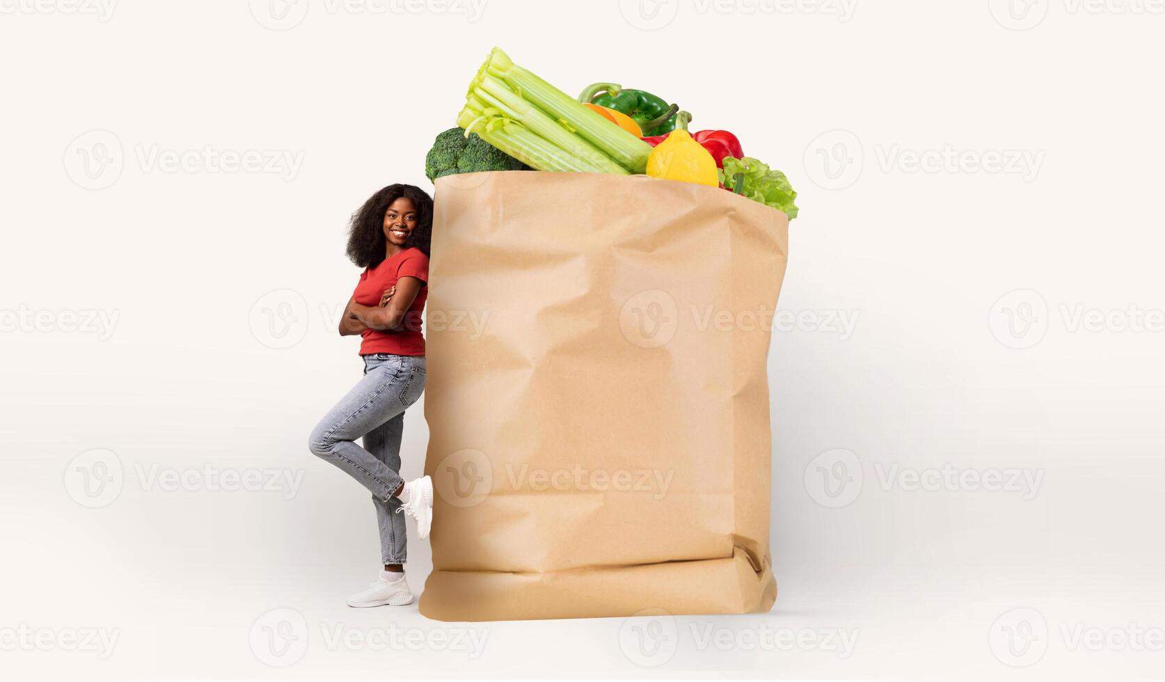 A customer leans against a large paper bag filled with fresh groceries, showcasing a mix of vegetables. The atmosphere reflects the recent trend of isolated shopping and delivery services. photo