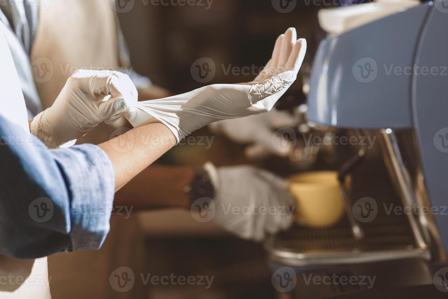 Good morning and start of day. African american bartender puts on gloves to work on espresso machine and prepare takeaway coffee for clients during covid-19 pandemic and social distancing, cropped photo