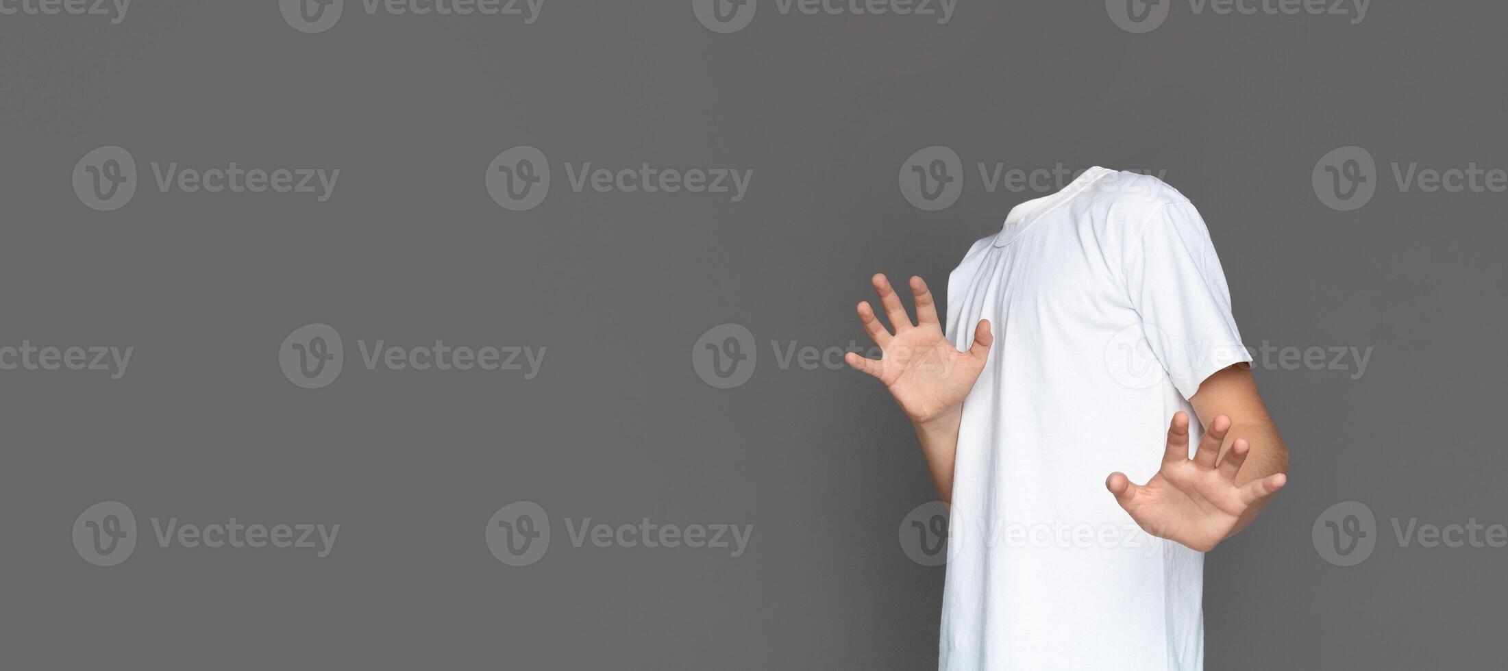 A headless figure in a plain white t-shirt poses against a blank gray background. photo