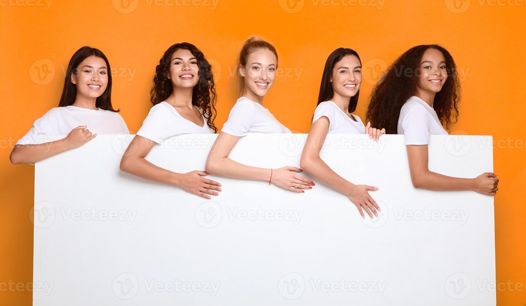 Happy Women Holding Blank Poster For Text Smiling To Camera Standing On Yellow Background In Studio. Mockup photo