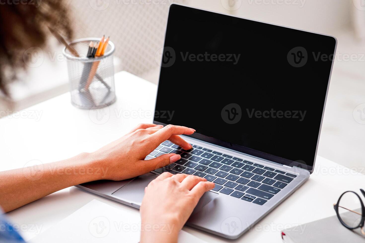 African american girl using laptop for online meeting in call with empty screen to work at home in self-isolation during quarantine. Cropped, close up photo