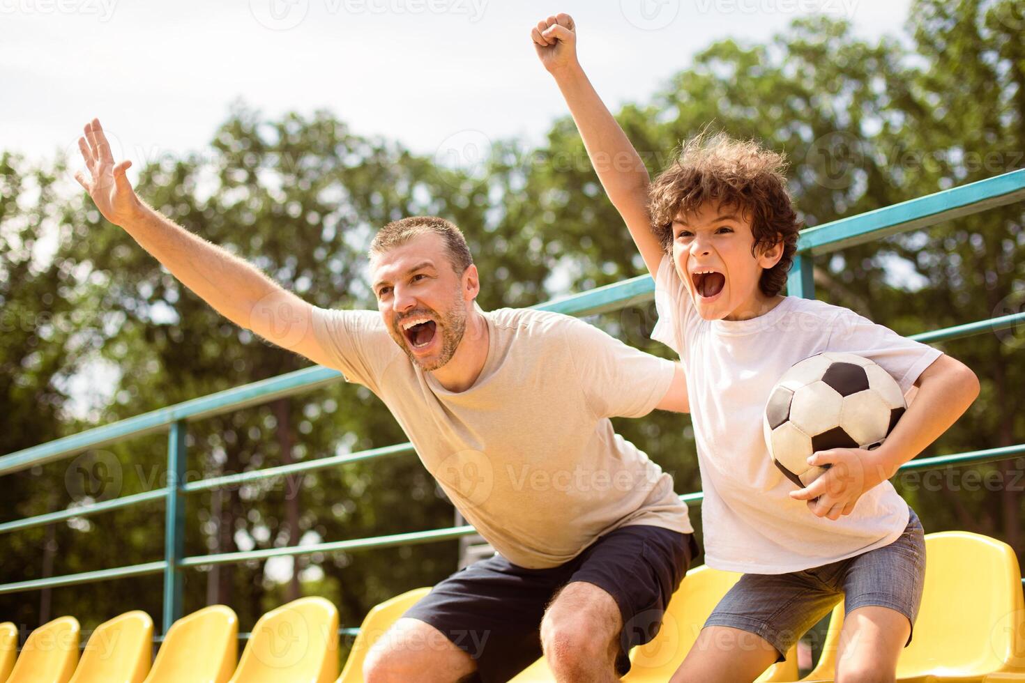 Win Concept. Happy family of two watching soccer game on playing field, screaming and celebrating victory photo