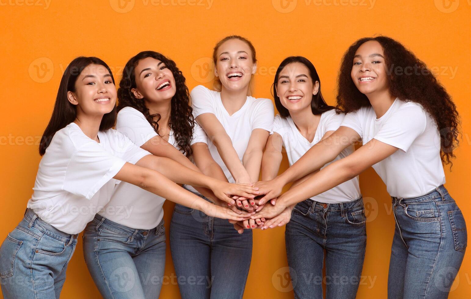 Five Diverse Girls Holding Hands Smiling To Camera Posing On Yellow Studio Background. Female Unity Concept photo