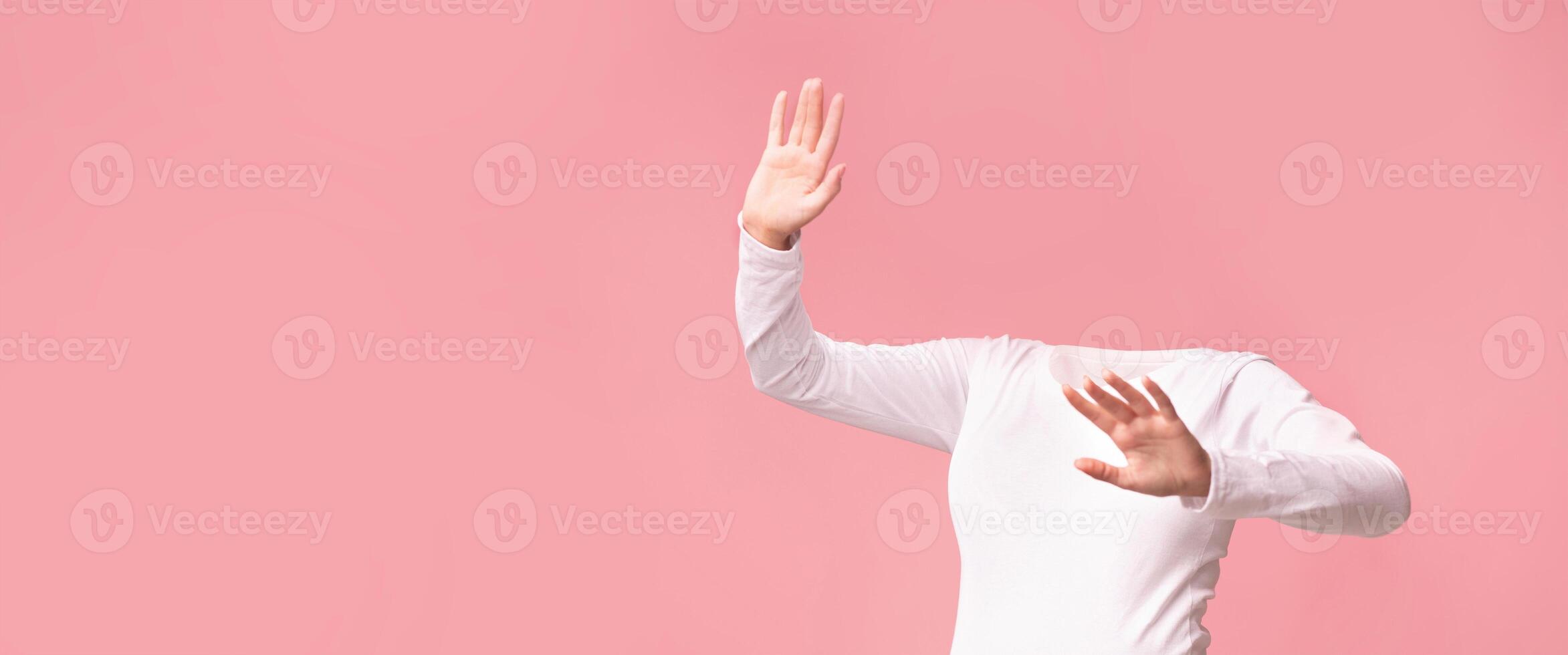 A headless figure in a white long-sleeve shirt poses against a soft pink background, emitting a playful vibe. The composition focuses on body language and movement, evoking a sense of whimsy. photo