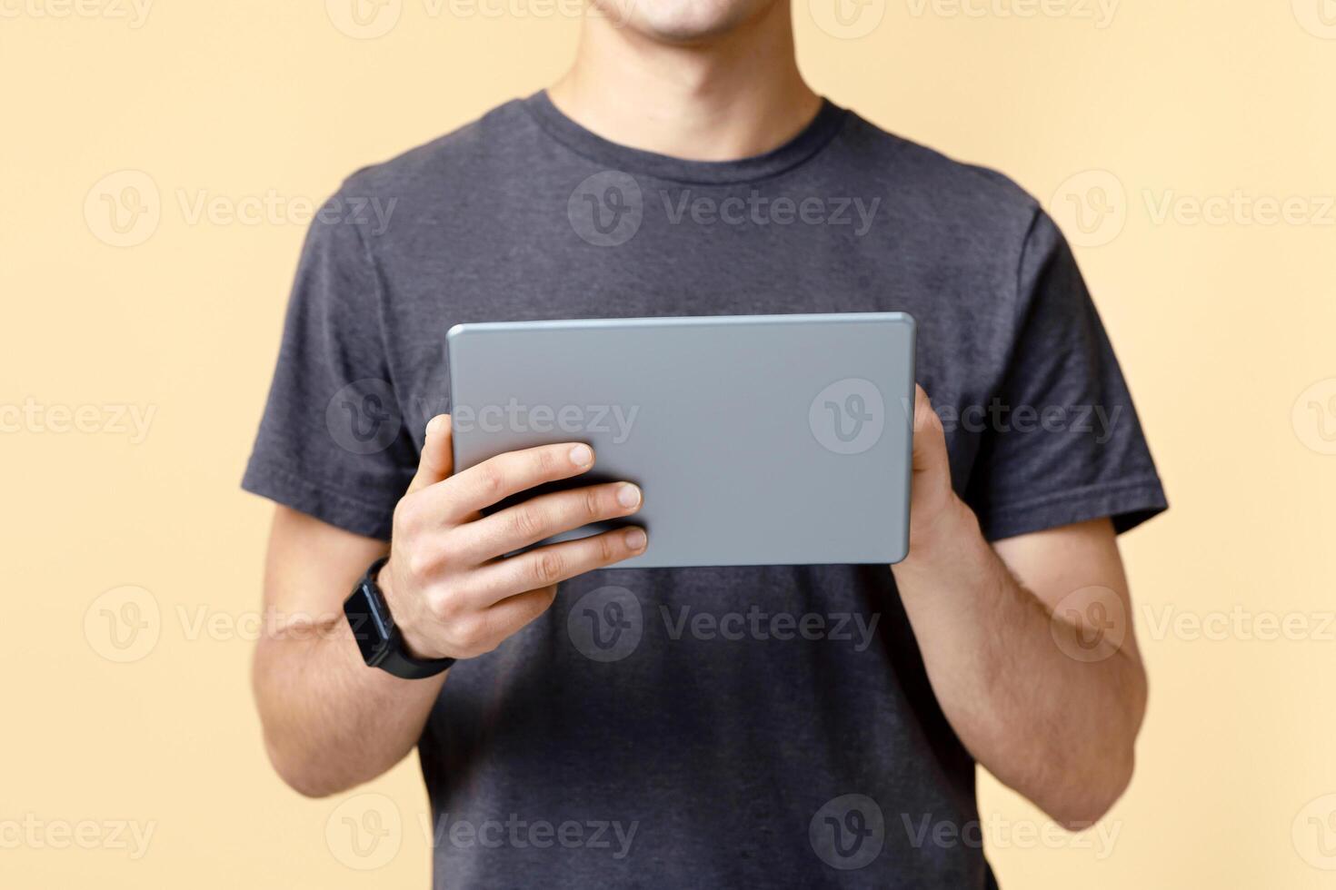 Work of freelancer or blogger with mobile gadget and application. Young man with smart watch typing on digital tablet, isolated on beige background, studio shot, free space, cropped, panorama photo