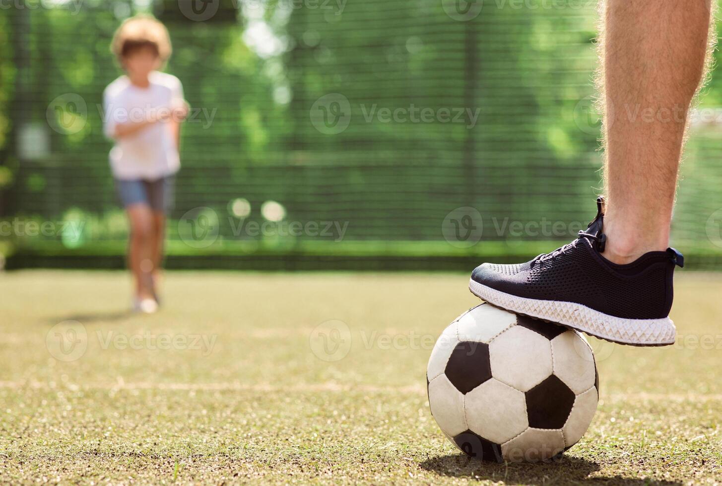 Close up of football player stepping on the soccer ball standing on green field, selective focus, blurred background photo