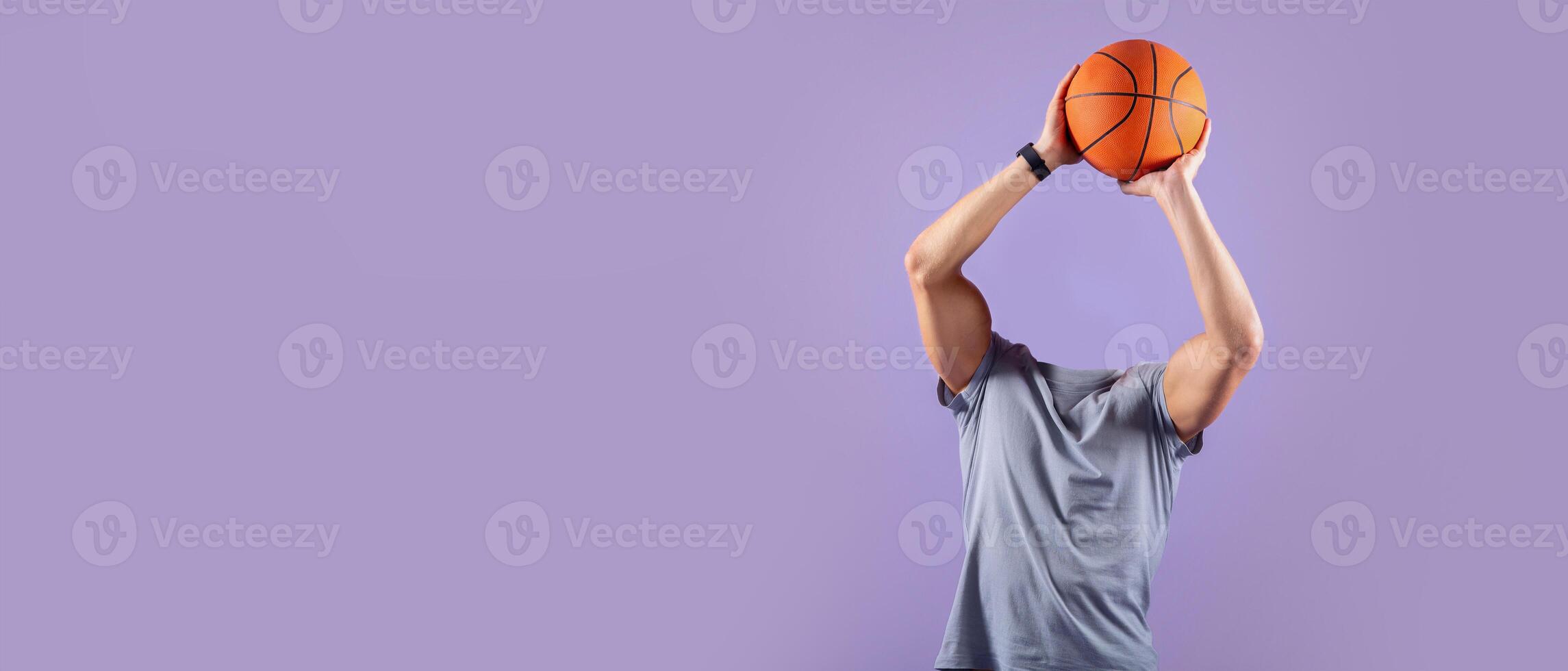 A headless basketball player is poised to shoot, with arms fully extended and holding an orange basketball. photo