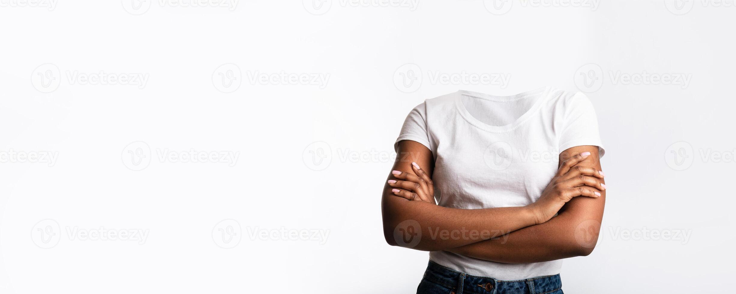 A headless individual stands with arms crossed, expressing confidence and poise. The plain background emphasizes the unique aesthetic of the lifestyle depiction, highlighting body language. photo