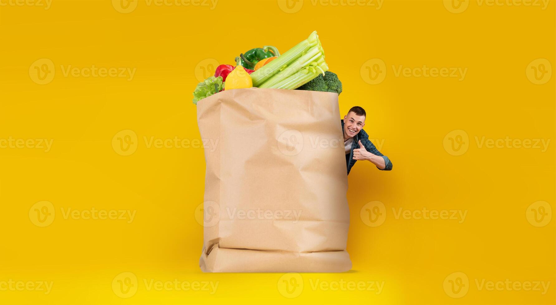 A customer stands next to a large paper bag filled with fresh groceries, showcasing vibrant fruits and vegetables. photo