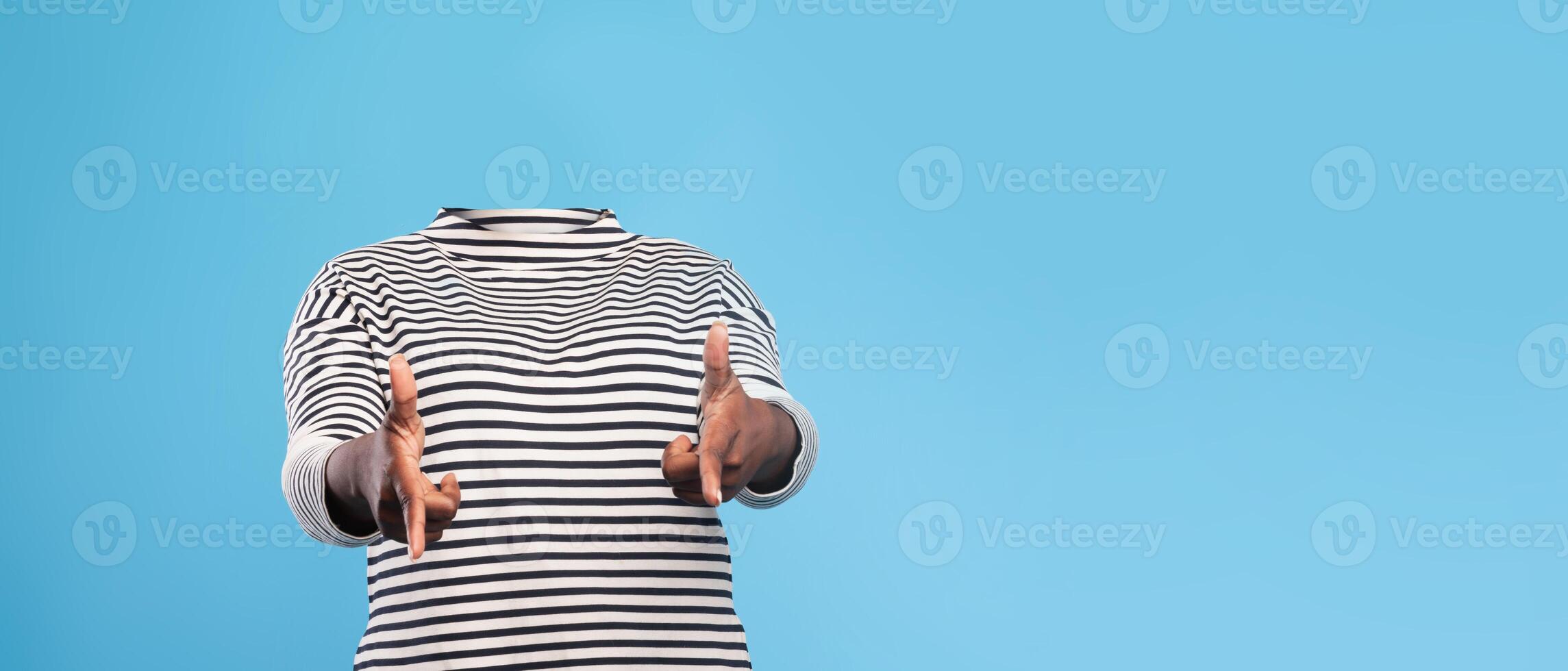 A person dressed in a striped shirt gestures expressively against a solid blue background. This headless portrayal emphasizes lifestyle uniqueness and artistic interpretation. photo
