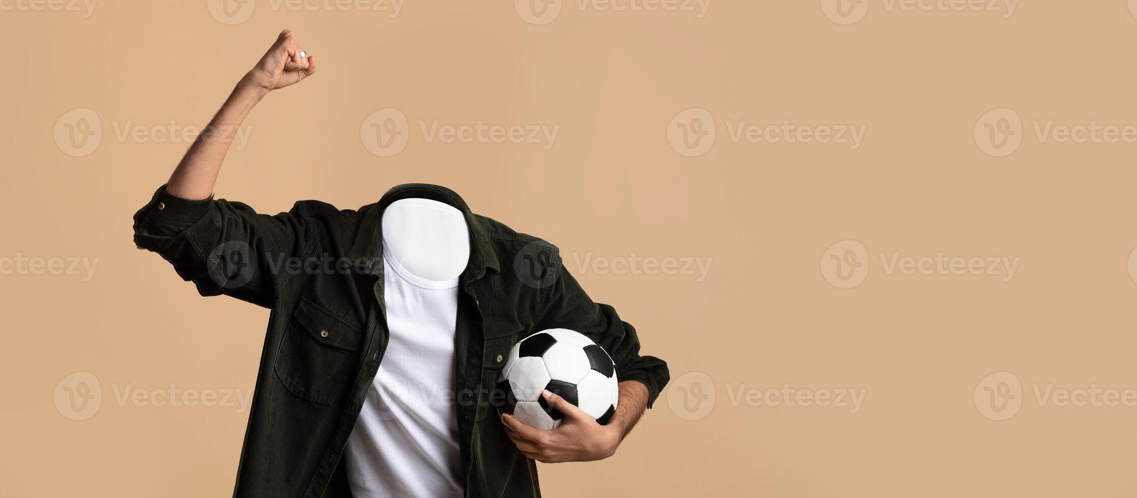 A person excitedly raises a fist in celebration, holding a soccer ball in the other hand. The individual is headless, showcasing a unique, playful lifestyle concept against a plain background. photo