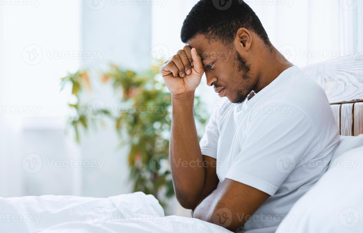 Male Depression. Depressed African American Guy Sitting In Bed Thinking About Problems In Bedroom At Home. Unhappy And Stressful Life And Troubles Concept. Empty Space For Text photo