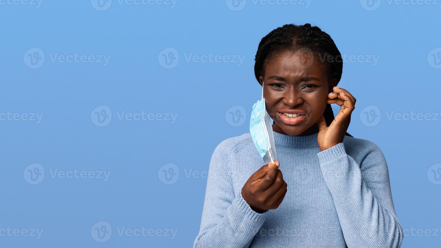 Itchy Face. Displeased Young Black Woman Scratching Skin After Wearing Protective Medical Mask, Having Allergy, Looking At Camera With Sad Expression, Isolated On Purple Background With Copy Space photo