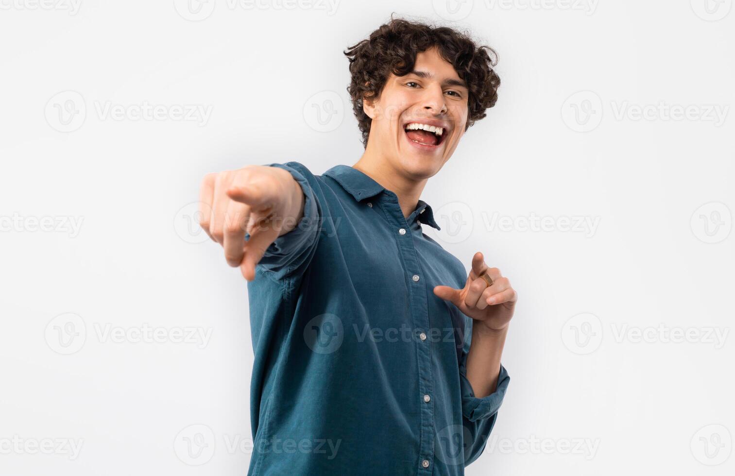 Hey You. Excited Curly Young Male Pointing Fingers Looking At Camera Choosing You Standing Posing Over White Background In Studio. You're My Choice Concept. Selective Focus photo