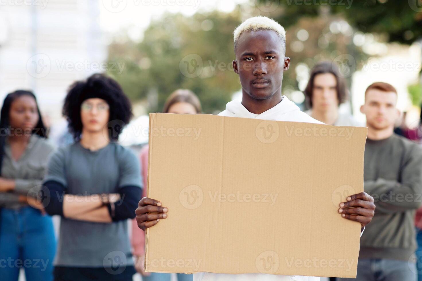 African american guy with empty placard for text and taglines leading group of young multiracial protestors. International group of demonstrators fighting against racism, standing on the street photo