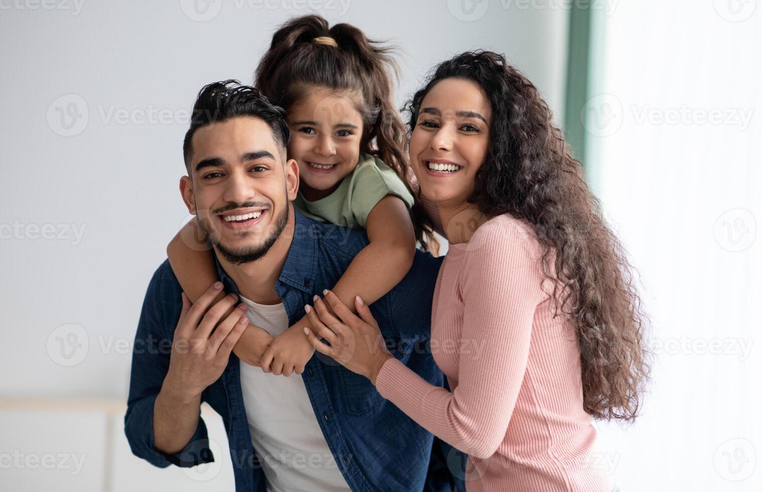 Portraif Of Happy Young Arabic Family Of Three With Little Daughter. Middle Eastern Mom, Dad And Kid Having Fun While Posing At Home, Parents Enjoying Spending Time With Their Child, Free Space photo