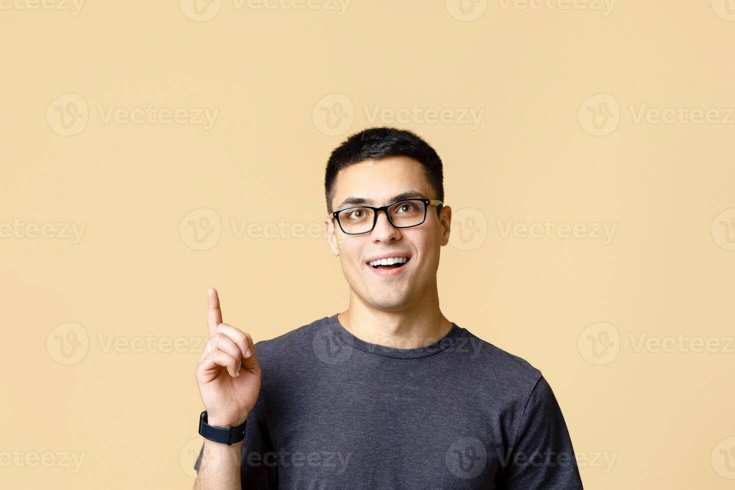 Smart student model ready to learn and shocked by offer. Surprised young zoomer guy with open mouth in glasses show thumb up to empty space for advertising, isolated on light background, studio shot photo