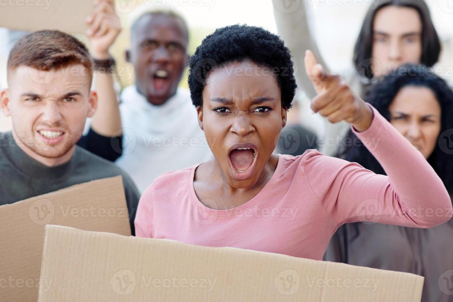 Angry international group of demonstrators protesting on the street, holding blank placards. Multiracial group of demonstrators fighting against racism, walking by the city, chanting slogans, closeup photo