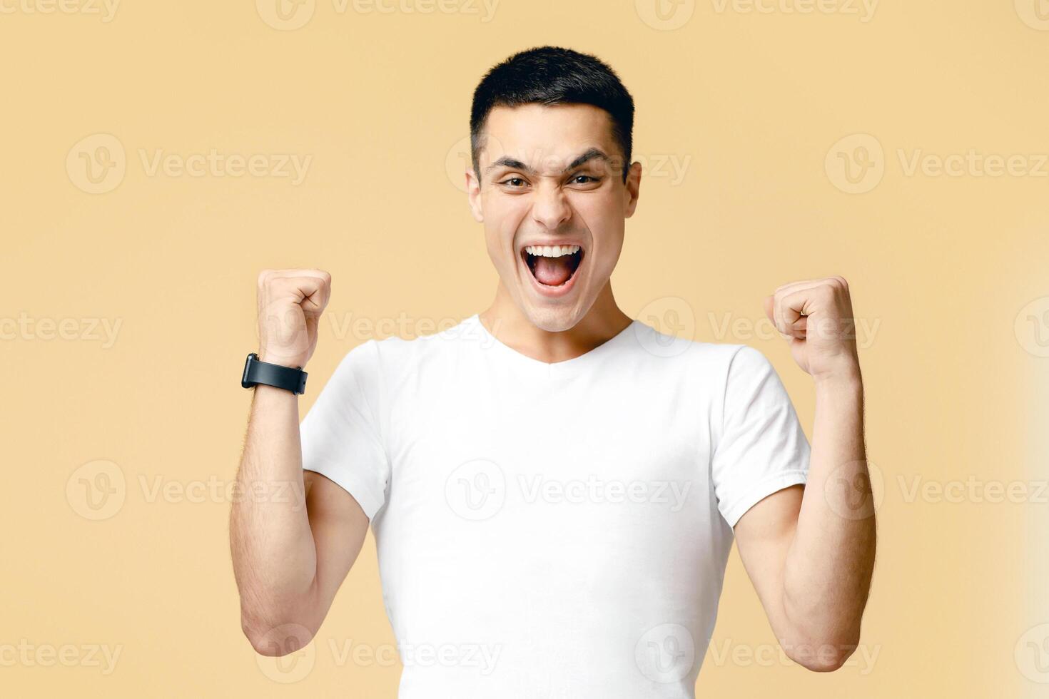 Really impressive achievements, win dance, rewarded, positive news. Successful young man shouts, raise hands up celebrates victory, isolated on light background, empty space, studio shot photo