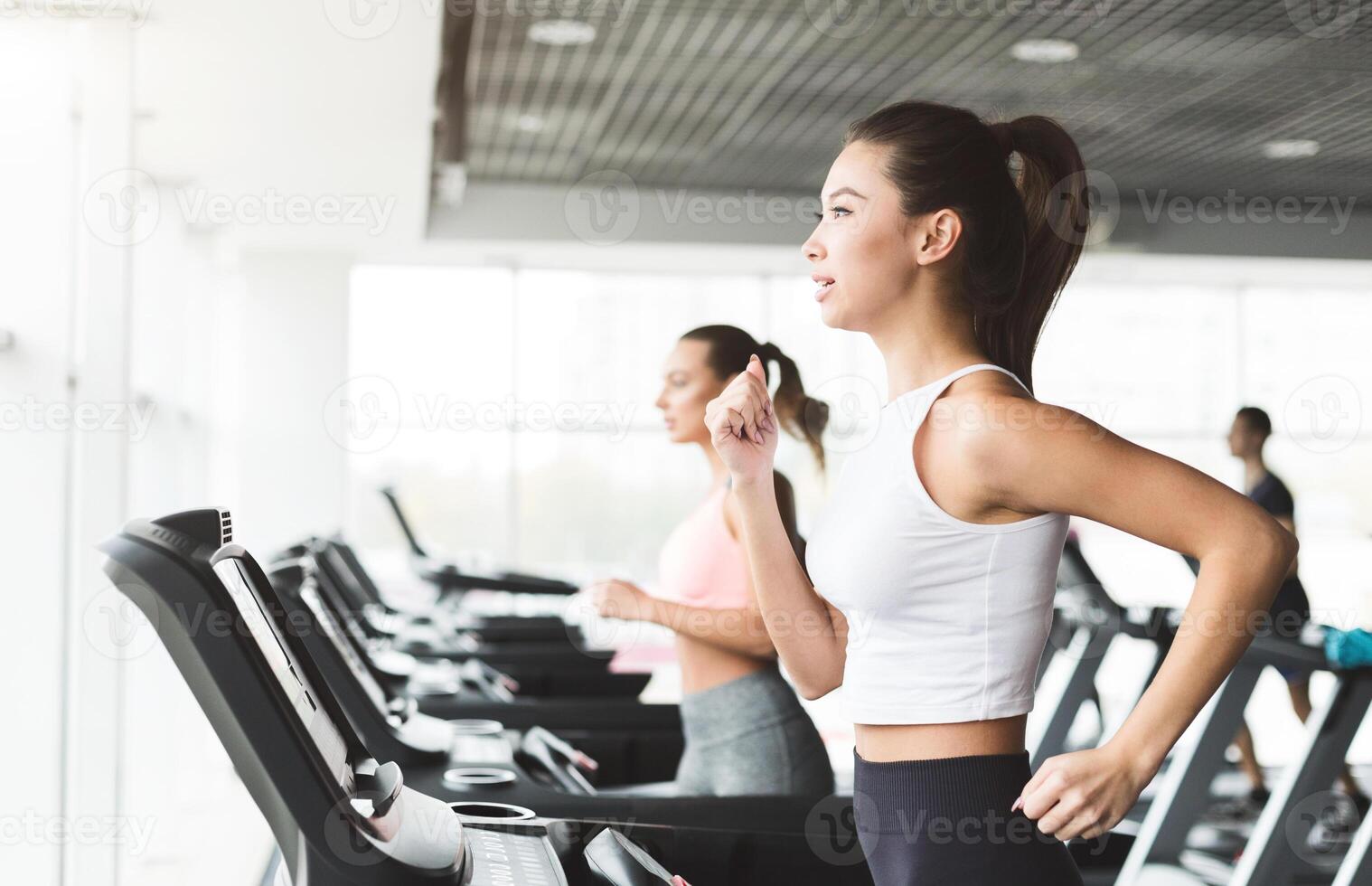 Asian girl working out on treadmill at the gym, side view, copy space photo