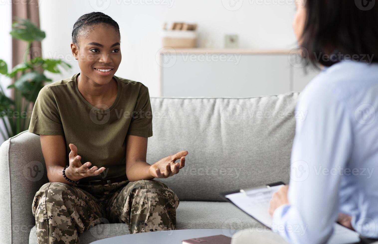 Happy Black Soldier Woman Talking To Female Therapist During Meeting In Office, Smiling African American Military Lady In Camouflage Uniform Speaking With Counselor After Successful Therapy photo