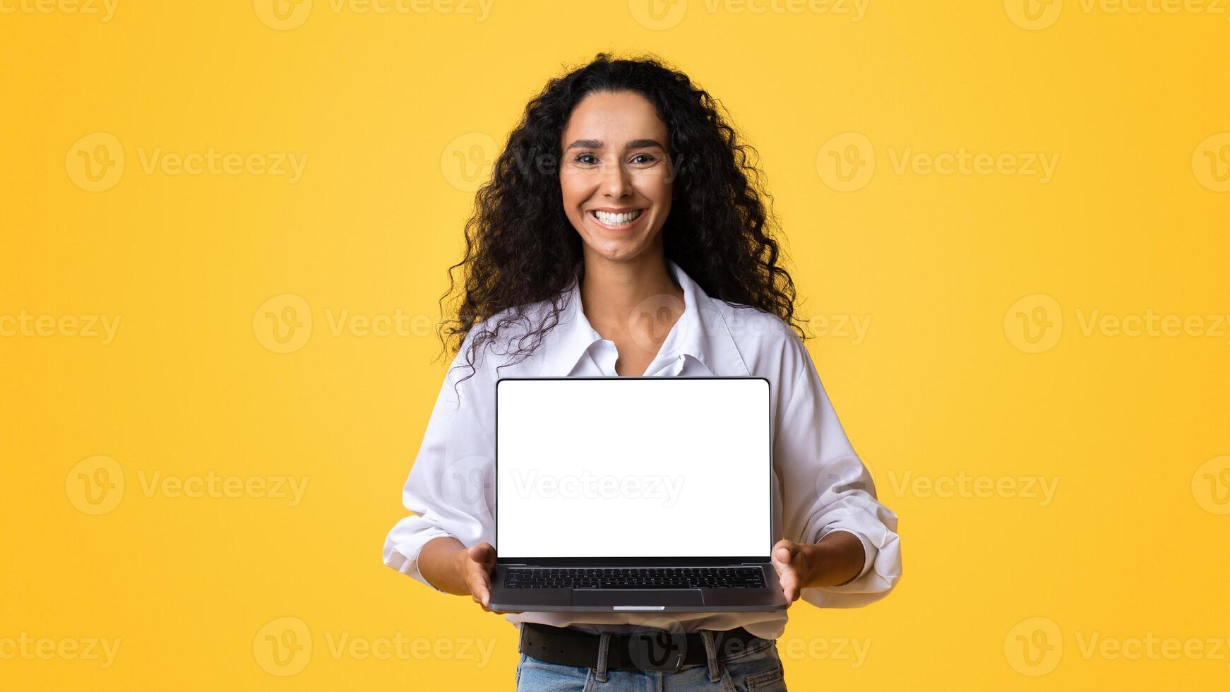 Check This Website. Happy Woman Holding Laptop Computer With Black Blank Screen, Isolated Over Yellow Background, Mockup Image With Copy Space, Template For Your Design, Free Place For Advertisement photo