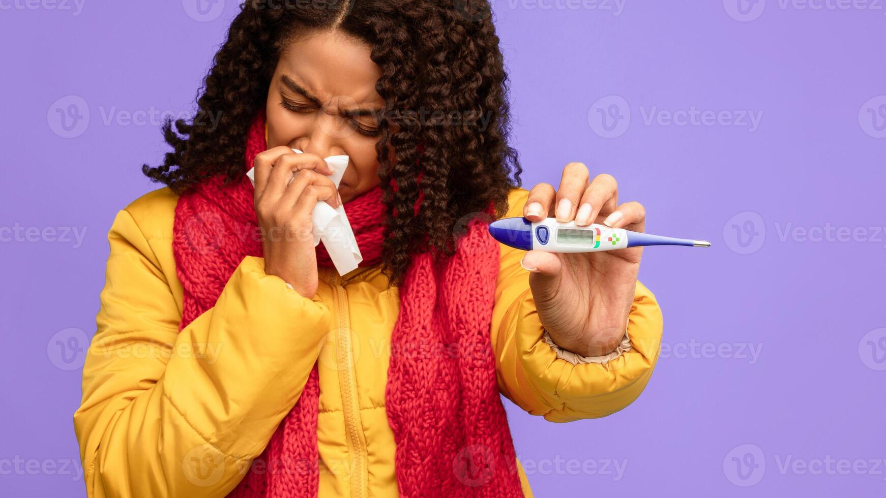 Fever Symptom. Sick Black Lady Showing Thermometer To Camera Sneezing In Tissue Standing On Blue Studio Background. Winter Cold And Flu Season, Coronavirus Disease Concept. Panorama photo