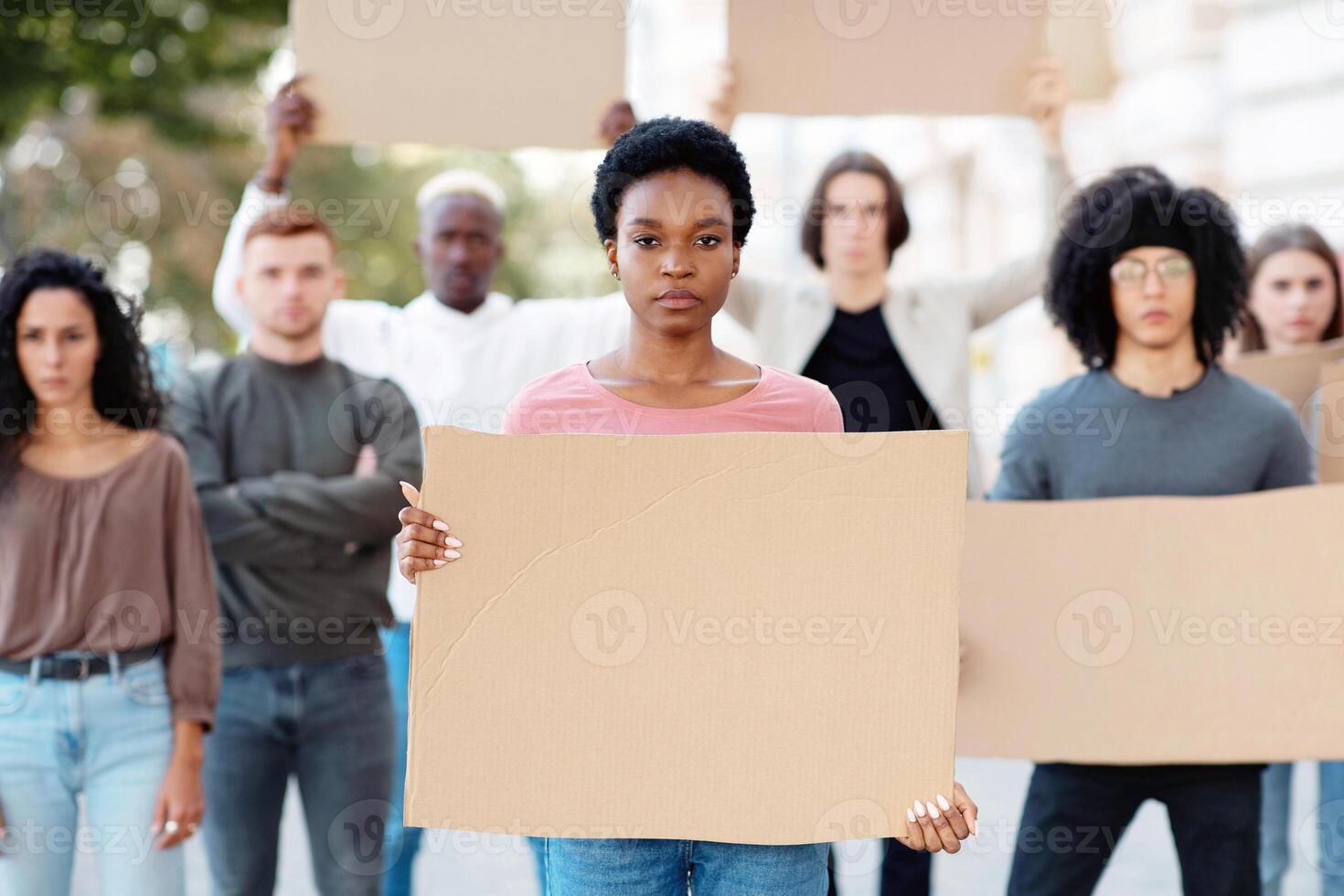 African american young woman leading a group of demonstrators on the street. International diverse group of people with empty placards protesting for human or animal rights and against racism photo