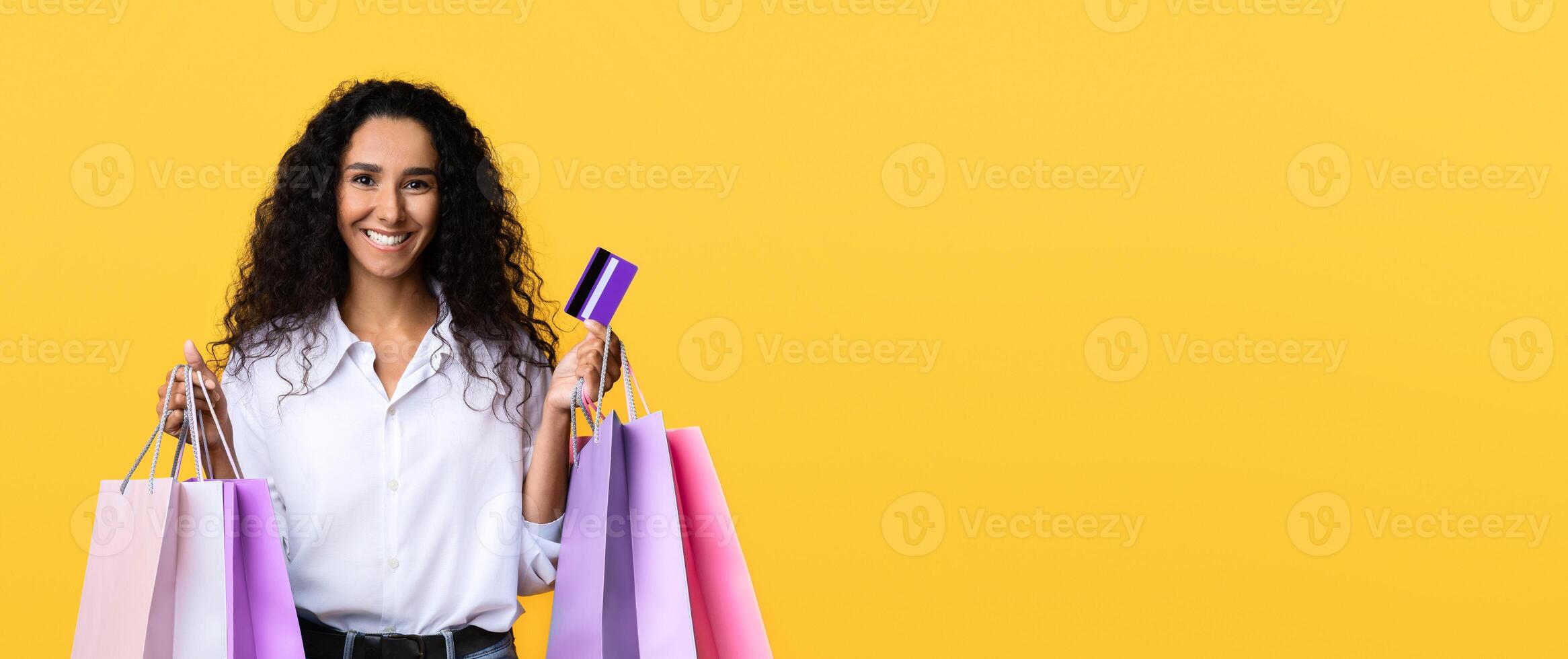 Easy Shopping. Happy Young Woman With Shopper Bags And Credit Card Posing Over Yellow Studio Background With Copy Space, Happy Shopaholic Lady Enjoying Seasonal Sales, Received Cashback Bonus photo