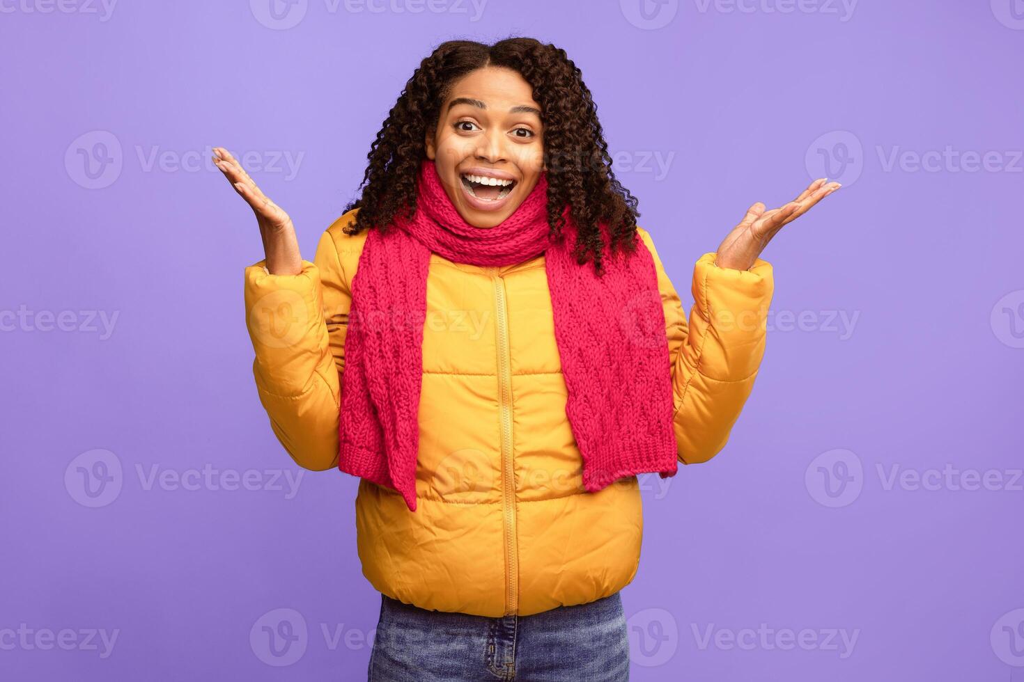 Excited African American Lady Looking At Camera In Surprise Gesturing With Hands Standing Over Blue Studio Background, Wearing Winter Jacket. Omg, Surprised Female Emotion Concept photo