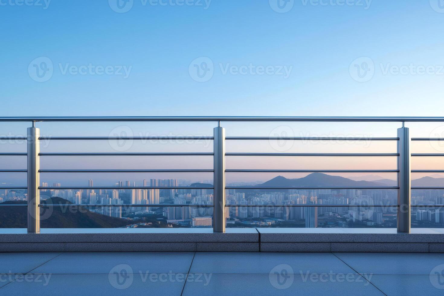 Modern cityscape seen from empty rooftop through metallic railing at sunset photo