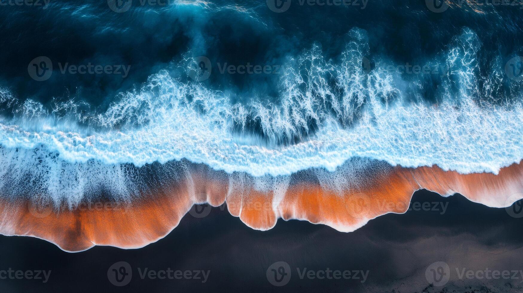 Ocean waves crashing on black sand beach creating orange foam lines photo