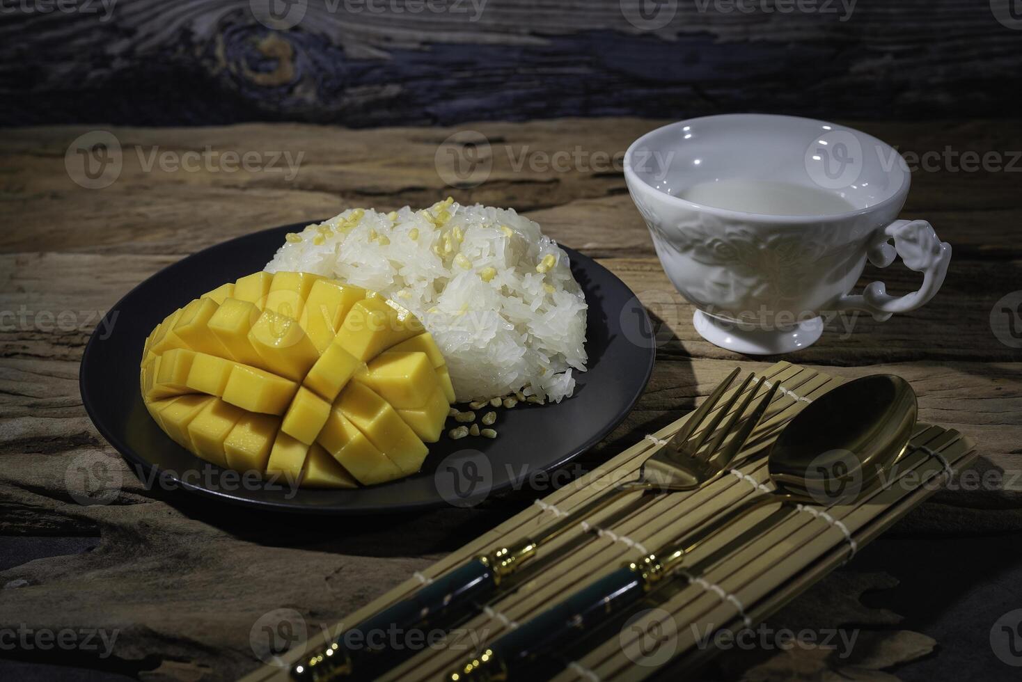Mango sticky rice, a Thai dish set against an old wooden backdrop. This dish is very popular in most Asian countries. photo