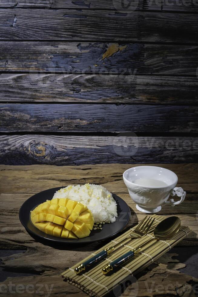 Mango sticky rice, a Thai dish, with an old wooden backdrop. This dish is very popular in Asian countries, Thailand. photo