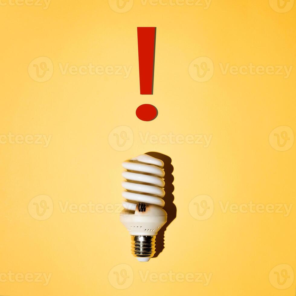 Burnt out energy saving light bulb. Danger sign. photo