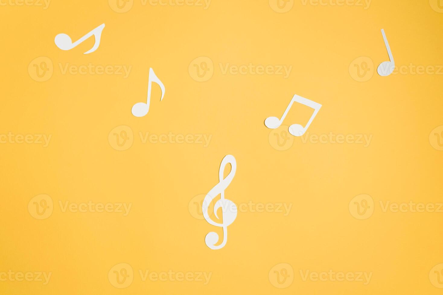 Musical notes and treble clef cut from paper, flat lay yellow background. Music layout top view. photo