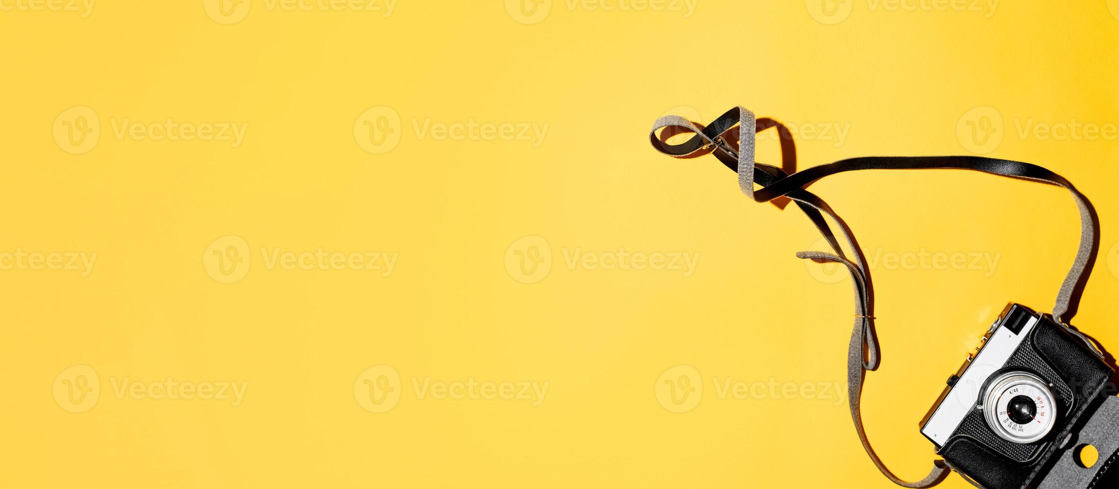 Vintage photo camera with a case on a yellow background. Copy space, flat lay. Retro film camera