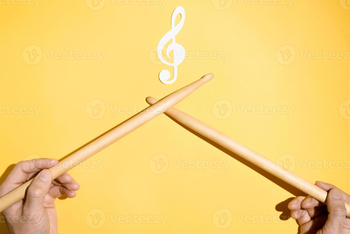 Drummer concept. Male hands holding drumsticks and a paper treble clef and musical treble clef. Flat lay photo