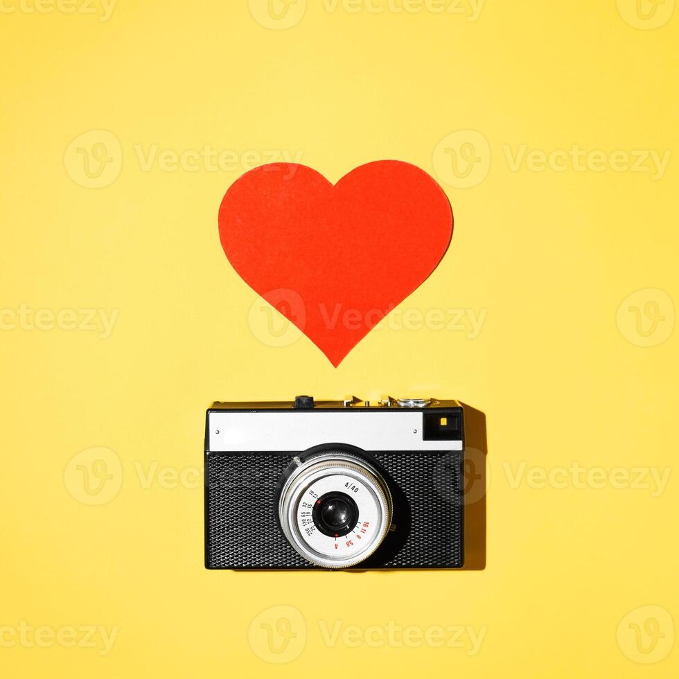 Vintage film camera and like heart on yellow background, flat lay. photo