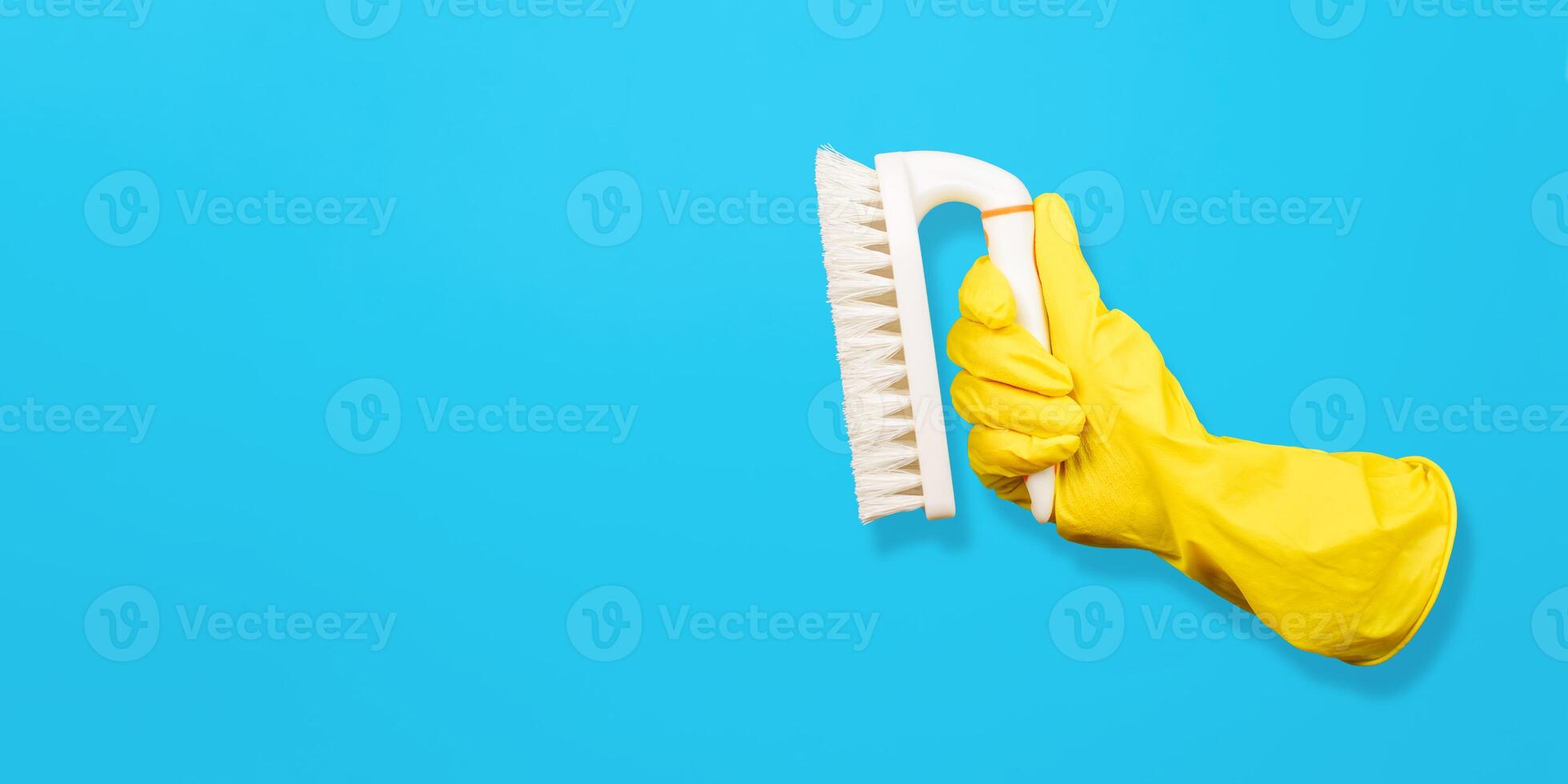 Flying glove holding cleaning brush. Blue background, copy space. Levitating objects. Creative concept for cleaning and washing equipment. photo