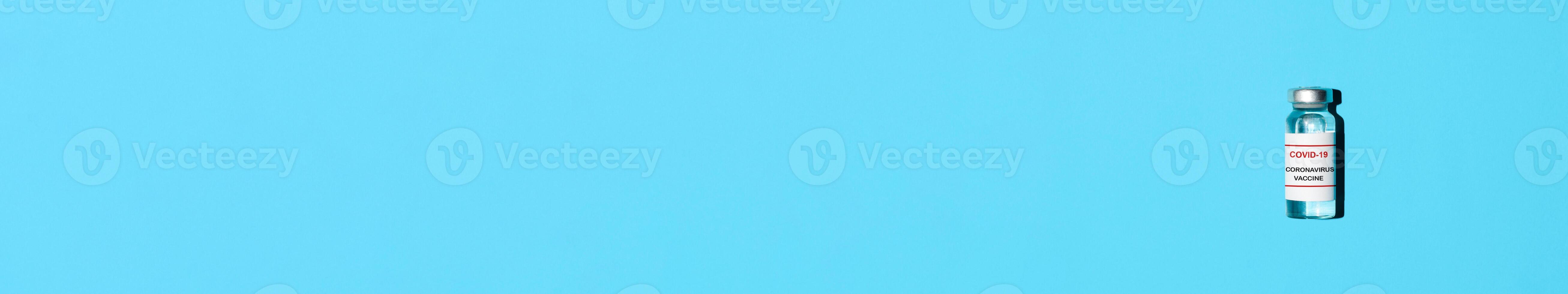 Vial of covid-19 vaccine. Flat lay banner. Blue background, copy space. Vaccination concept. photo